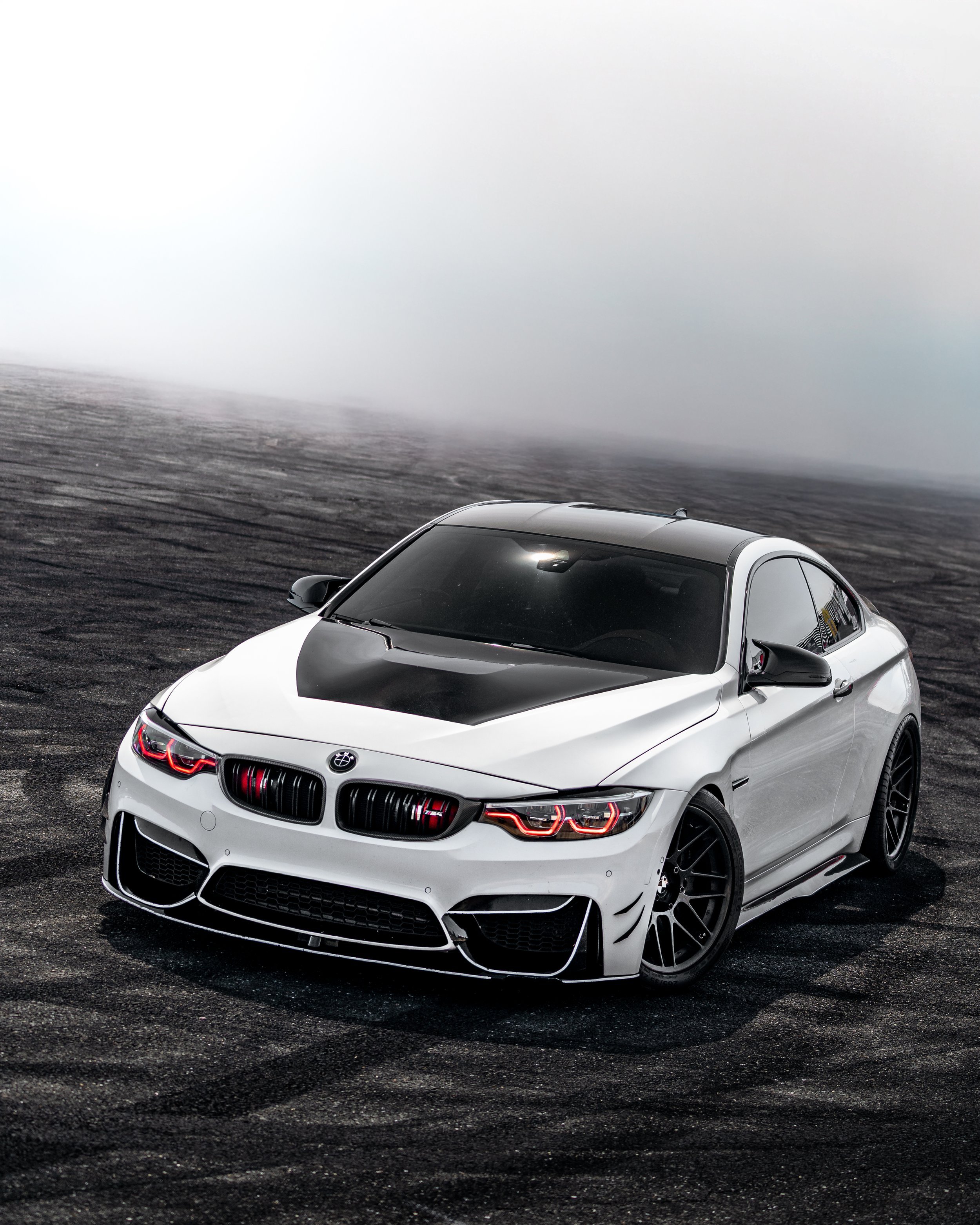 A black and white sports car parked on asphalt pavement with foggy background