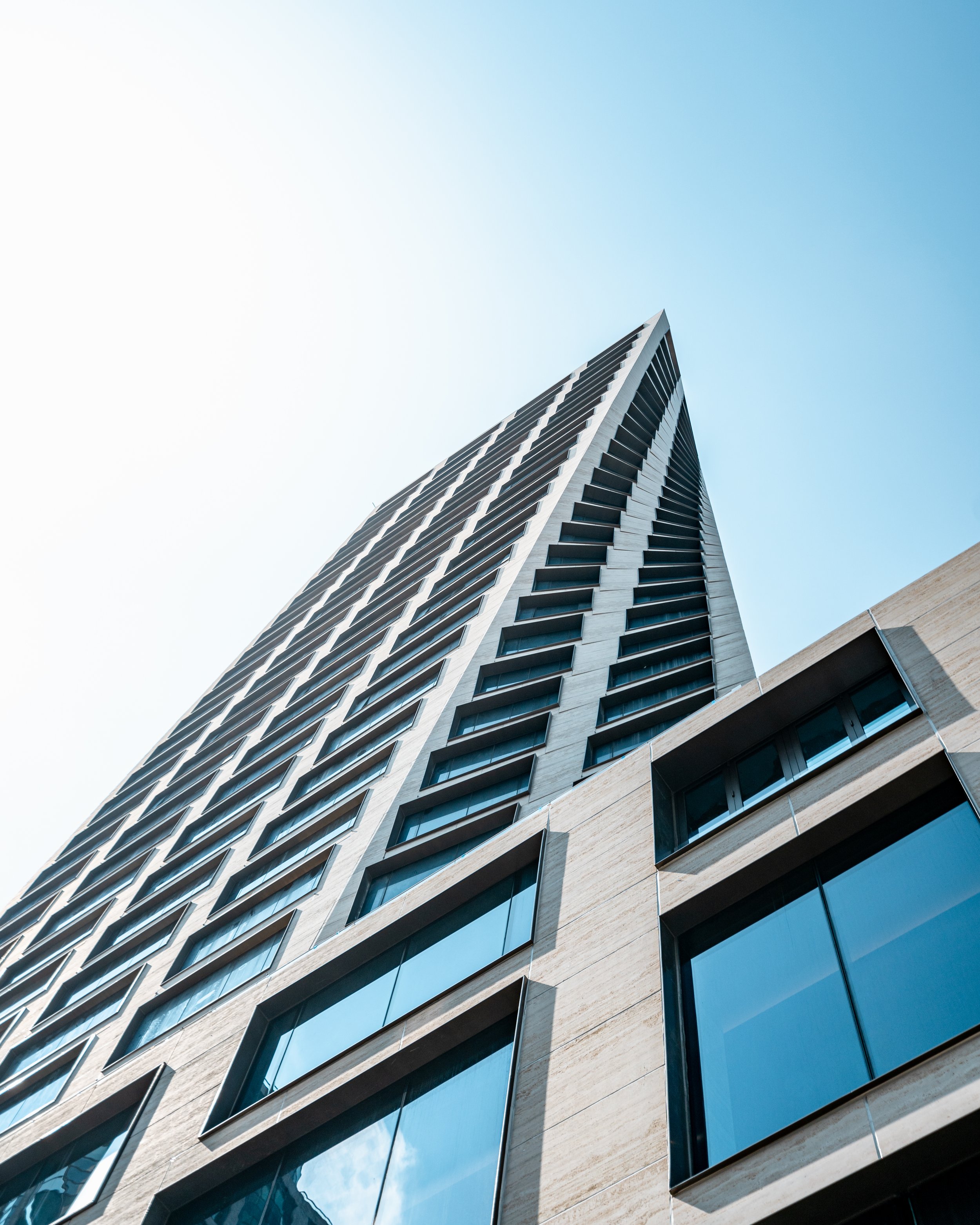 A modern high-rise building with many windows, viewed from a low angle against a blue sky in Manhattan 